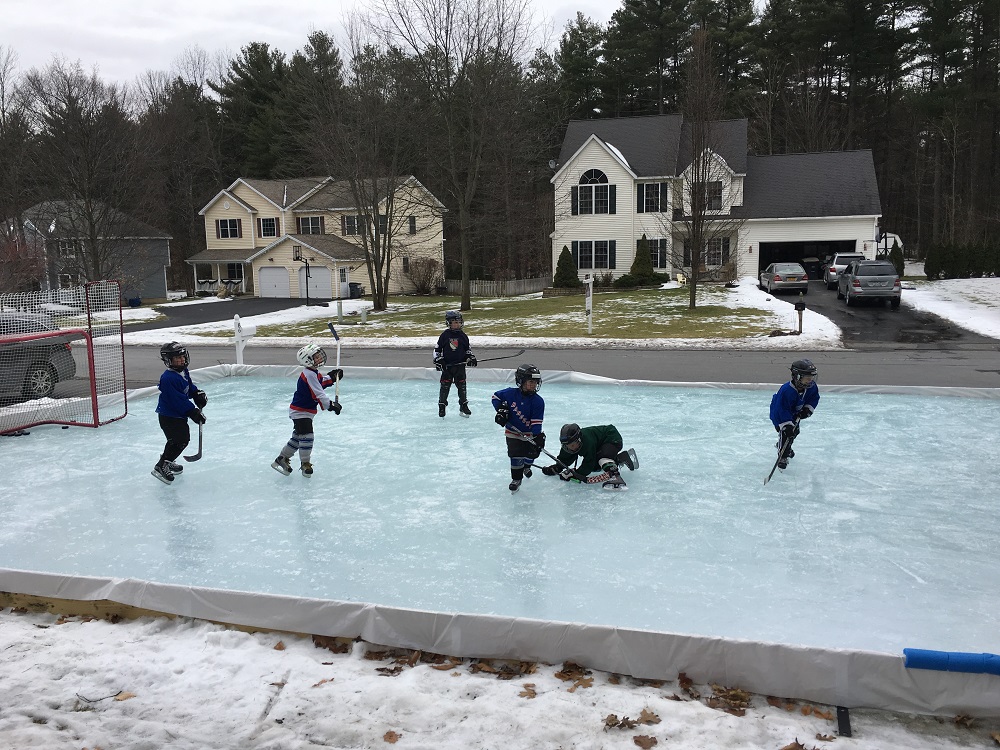 Residential ice rink with kids playing hockey.  Rink built with an Iron Sleek Rink kit.